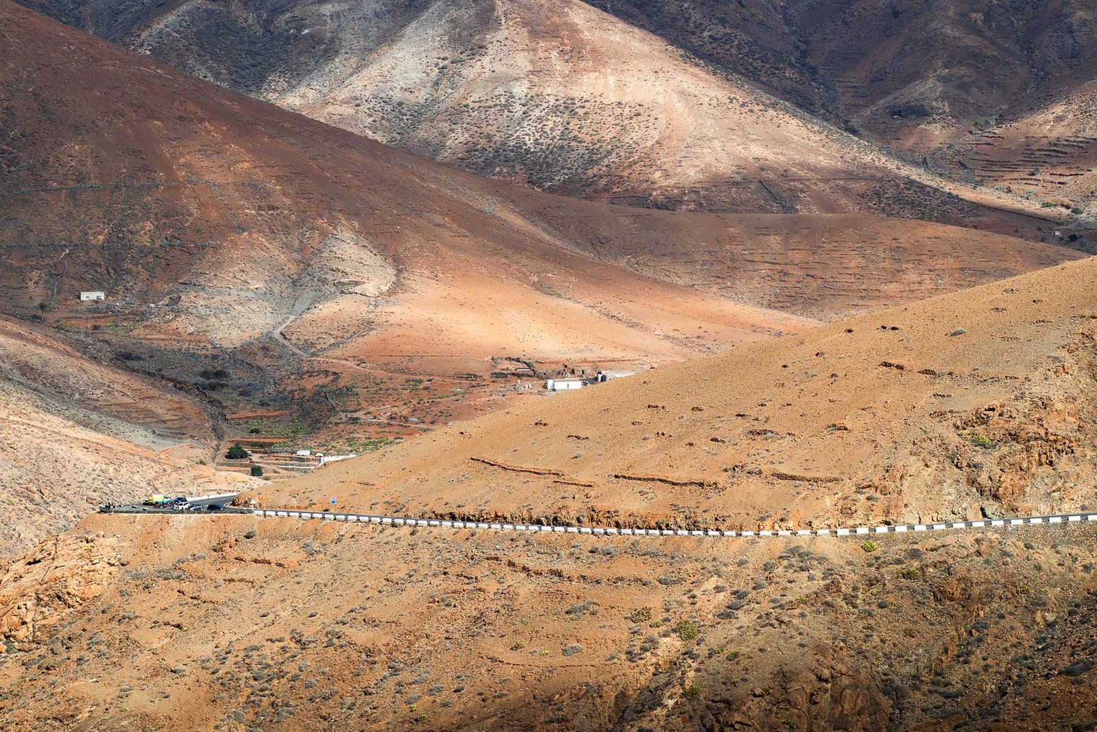 Carretera solitaria atravesando el paisaje volcánico y árido de montañas ocres del interior de Fuerteventura