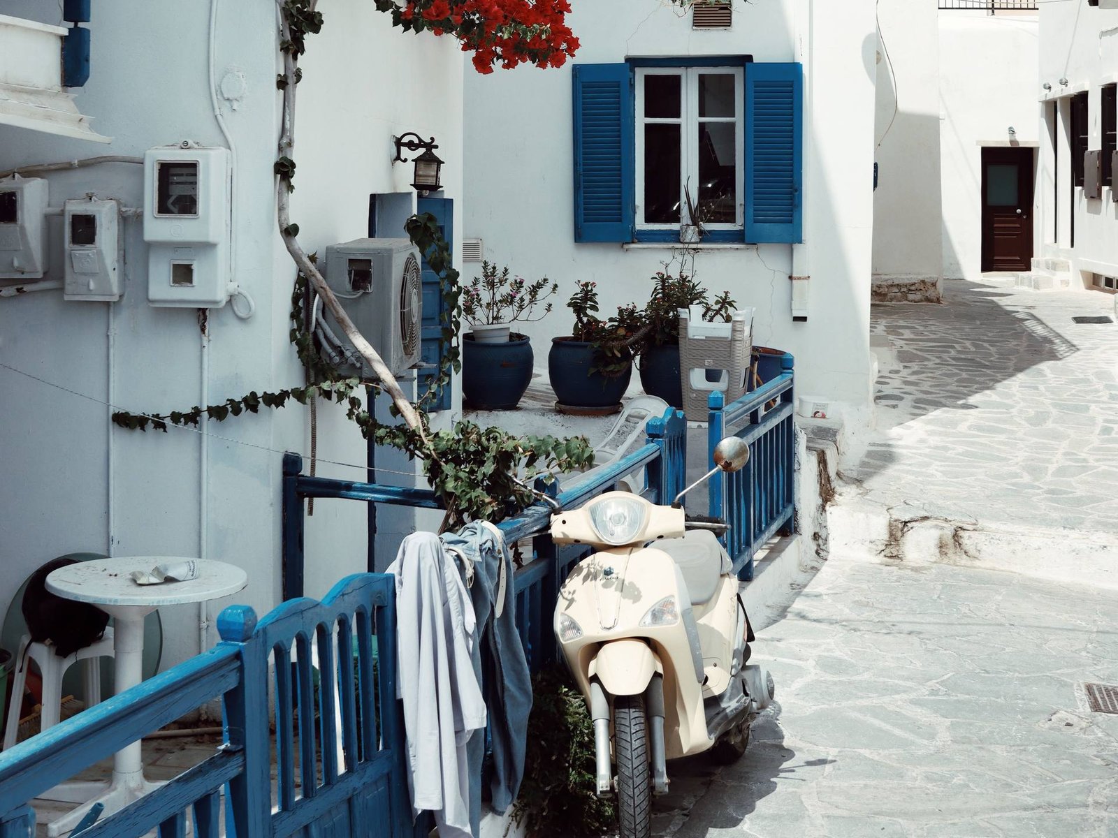Roller geparkt vor einer weißen Fassade mit blauen Fensterläden und Bougainvillea, der typische mediterrane Altstadtstil von Ibiza