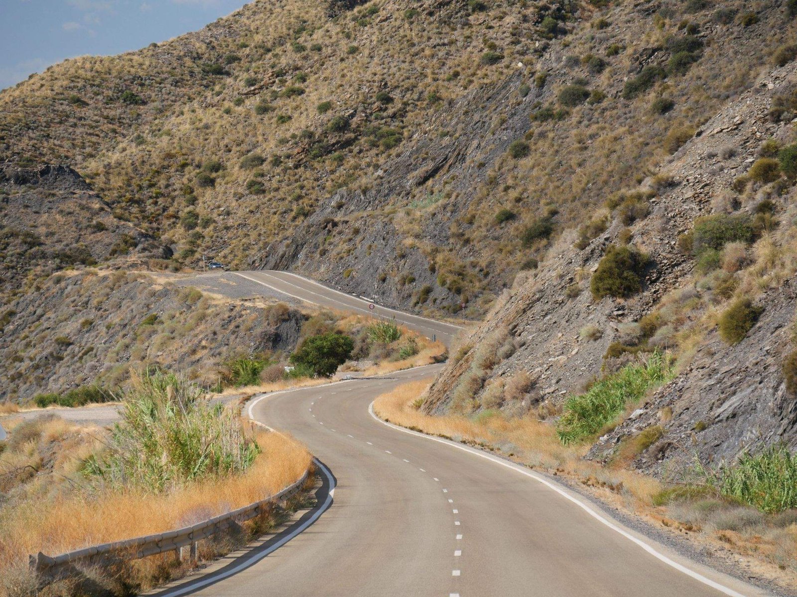Carretera de montaña con curvas entre cerros áridos, el tipo de trazado de puerto de montaña que caracteriza la Serra de Tramuntana en Mallorca